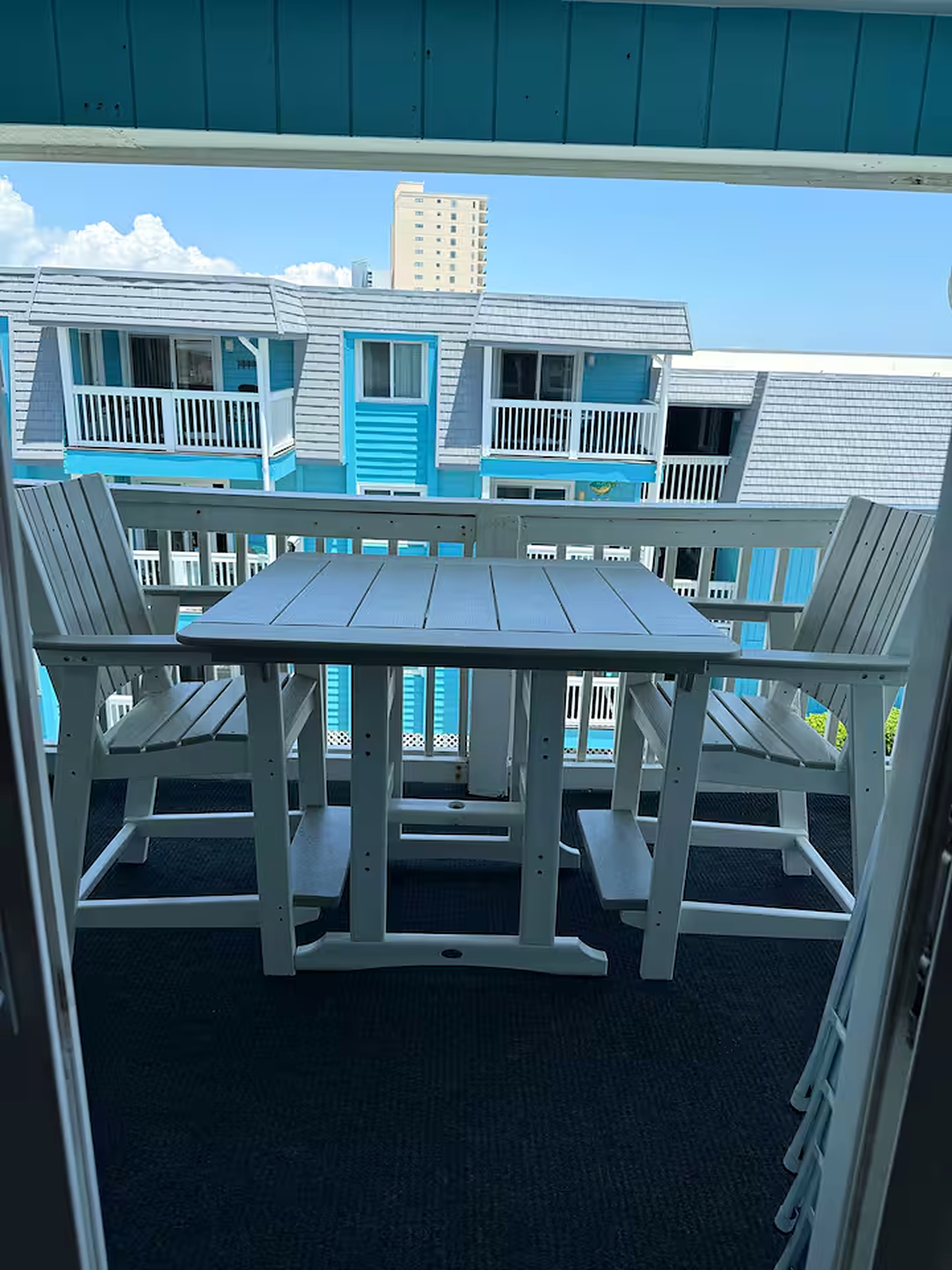 Private balcony with table and chairs overlooking the courtyard and pool