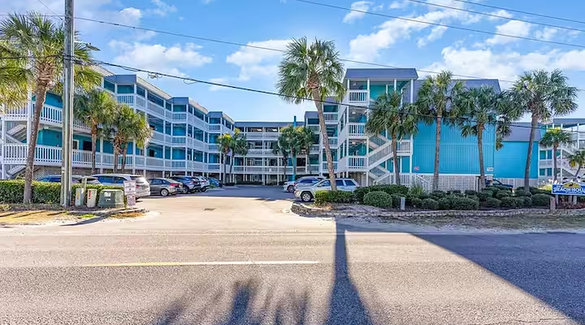 Exterior of the oceanfront condo complex in Garden City Beach with palm trees and on-site parking