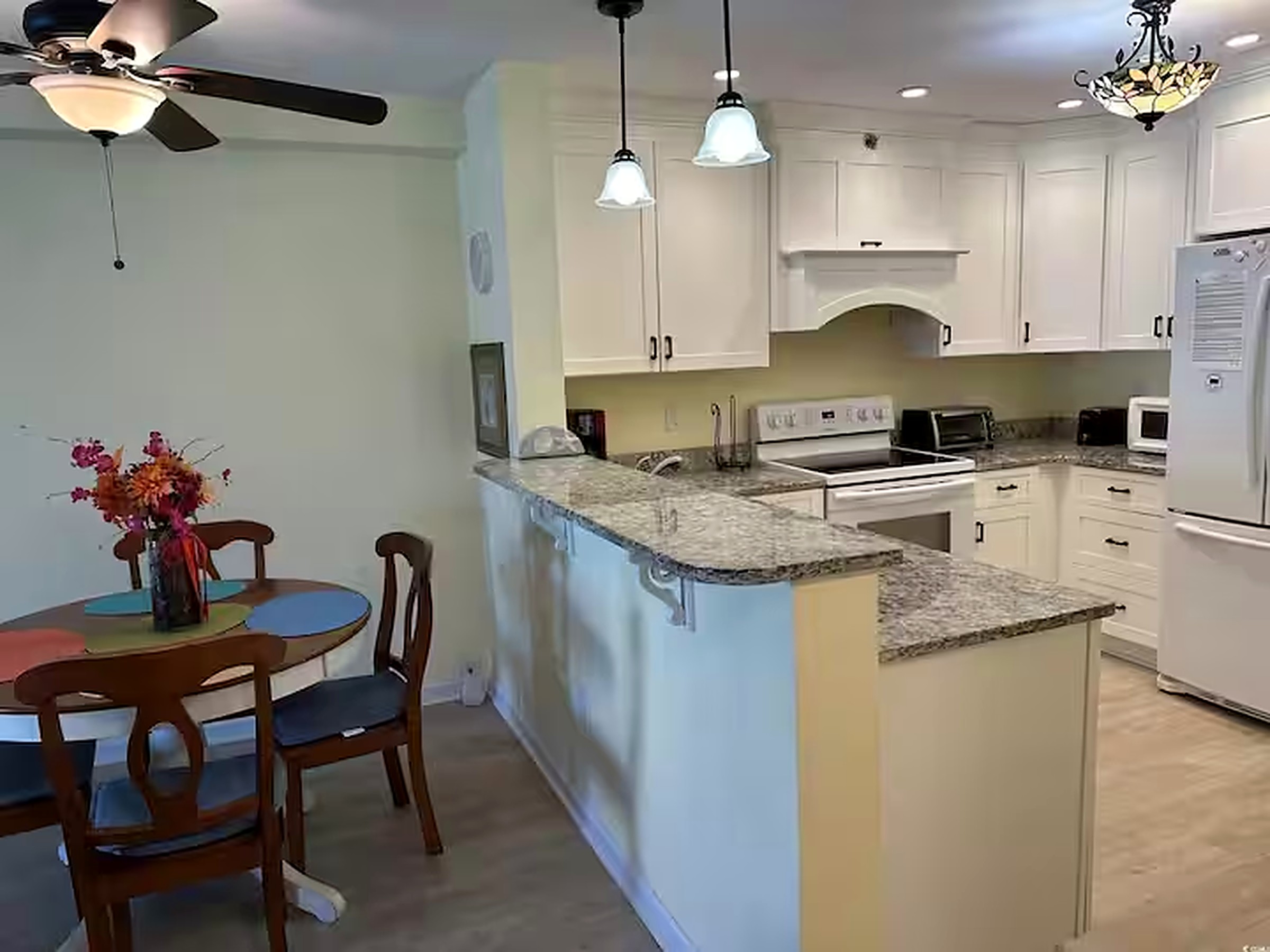 Open kitchen and dining area with breakfast bar seating and a dining table for four